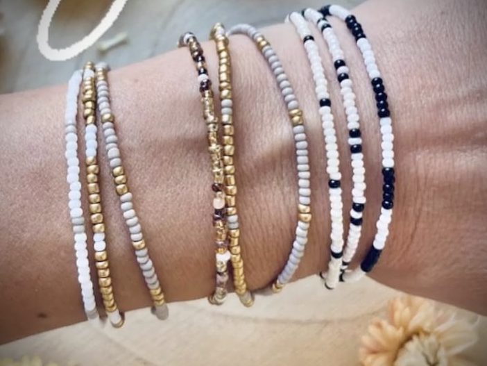 Perlenarmbänder Bunte Armbänder aus Perlen in Gold, Weiß, Schwarz und Bronze an einem Handgelenk.