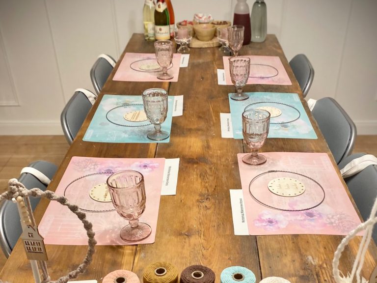 Workshopraum Tisch gedeckt mit rosa und blauen Platzdeckchen, Gläsern und Geschirr und Bastelmaterial