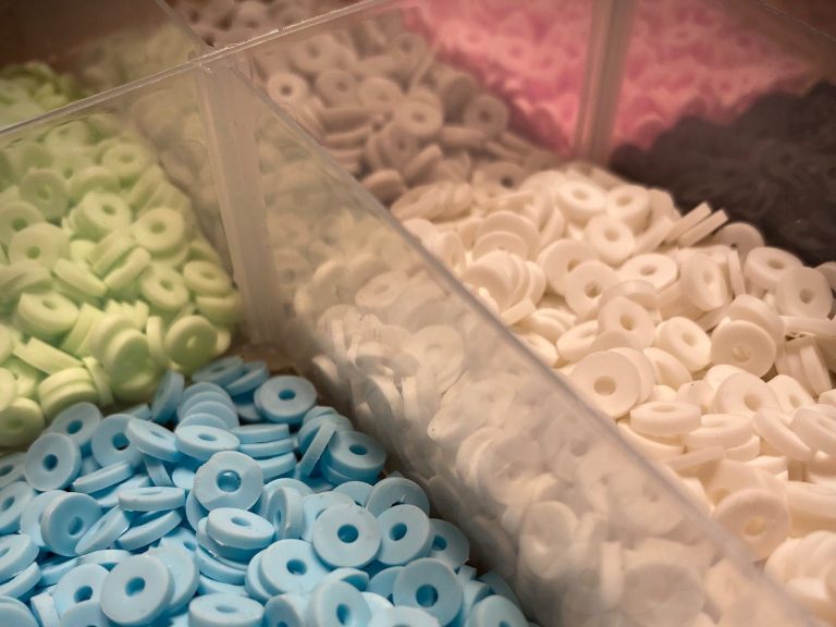Perlensortiment Bunte runde Perlen in verschiedenen Farben in durchsichtigen Behältern.