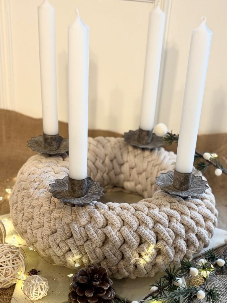 Adventskranz Dekorativer Adventskranz mit weißen Gebäuden und grauen Kerzen auf einer Holzplatte.